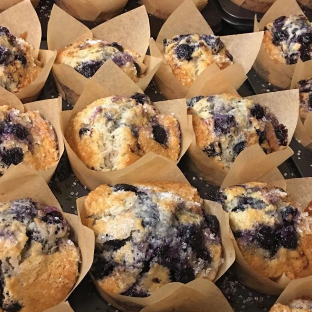 Blueberry muffins in brown paper tulip cups, topped with coarse sugar
